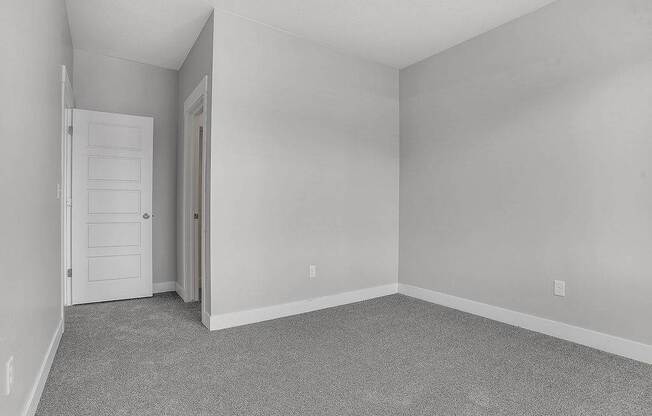 A room with a carpeted floor and a white door.