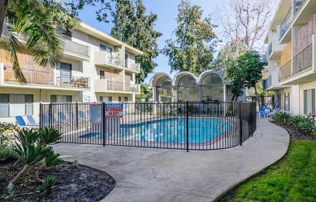 a swimming pool is behind a fence in front of an apartment building