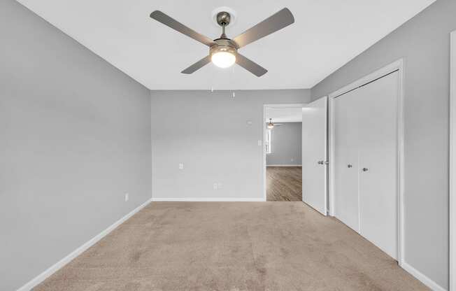 an empty room with a ceiling fan and a closet