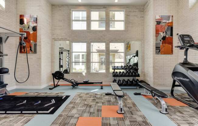 Fitness center with benches, free weights and rowing machine at Morgan Ranch Apartments, Morgan Hill, CA