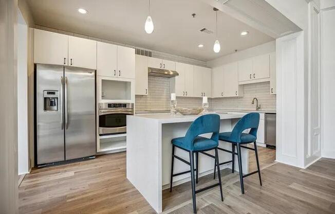 A kitchen with a white island and blue chairs.