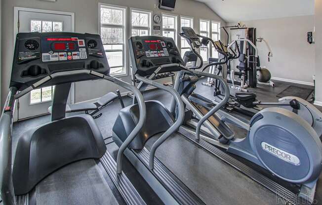 a gym with cardio equipment and windows in a home gym