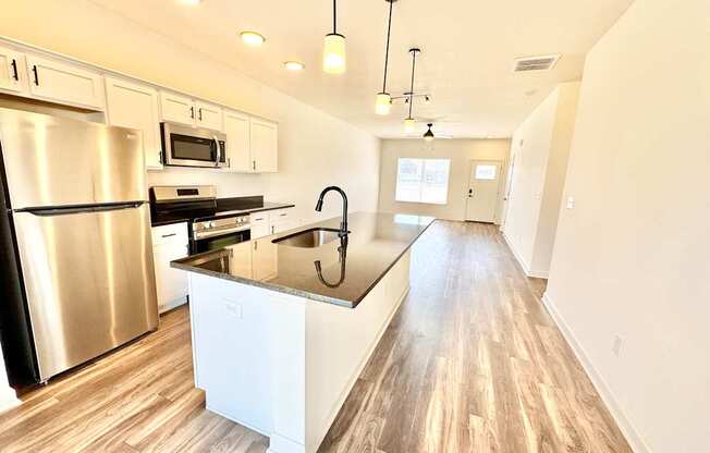 A modern kitchen with a stainless steel refrigerator and wooden flooring.