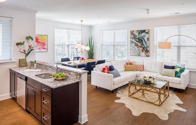 A modern kitchen with a white countertop and a white couch with colorful pillows.