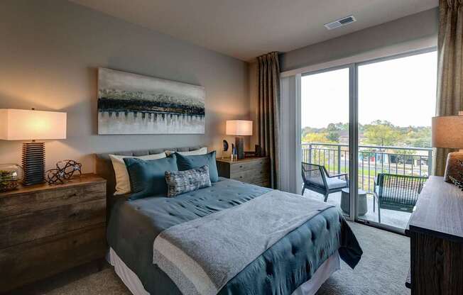 A bedroom with a large bed and a view of the outdoors through a sliding glass door.