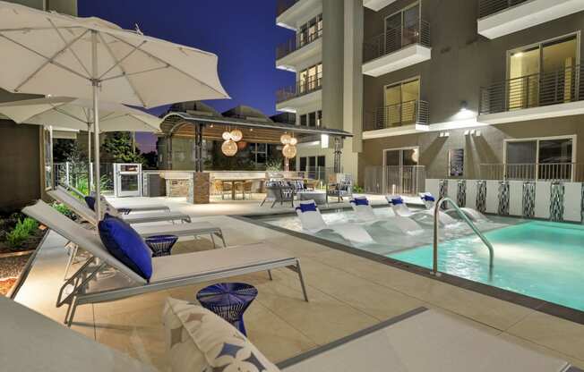 Pool with lounge deck and chairs at night