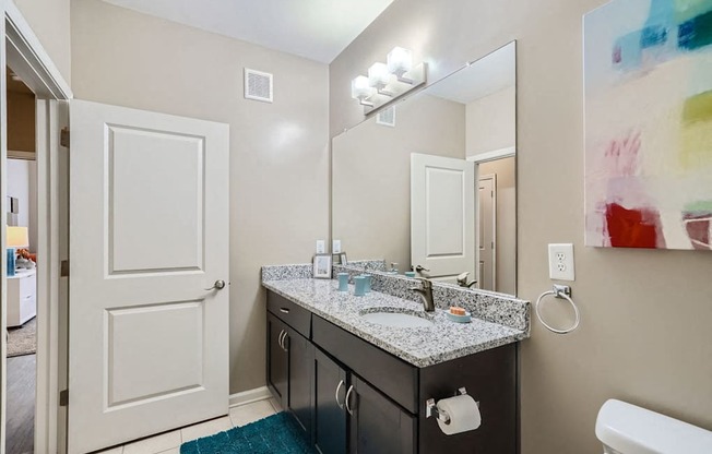 A bathroom with a sink, mirror, and toilet paper holder.