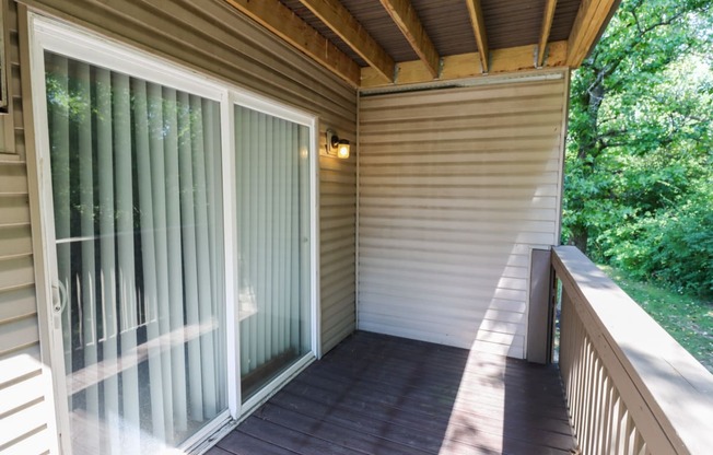 a covered porch with sliding glass doors and a wooden deck