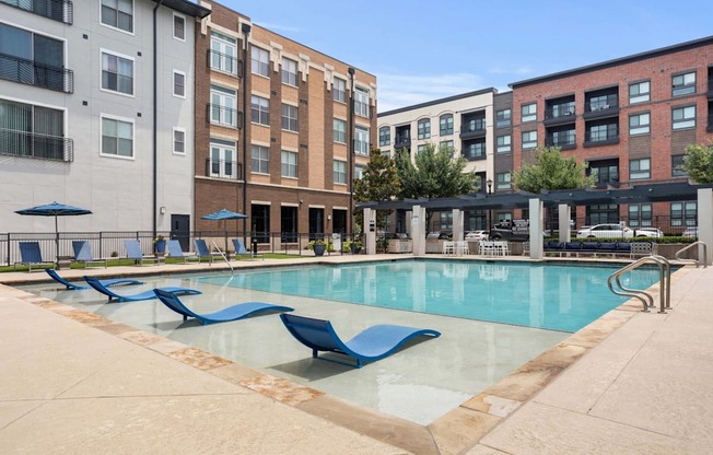 A pool surrounded by chairs and buildings.