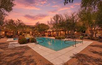 A pool surrounded by trees and a building in the background.