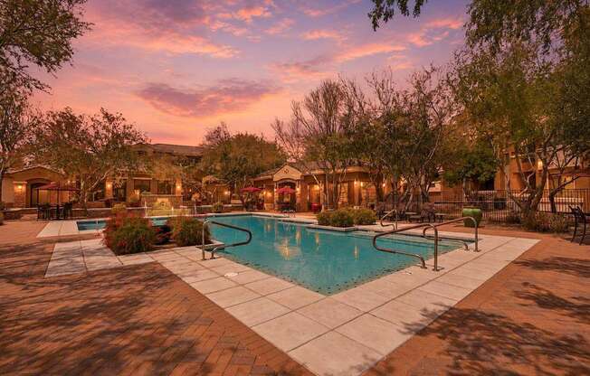 A pool surrounded by trees and a building in the background.