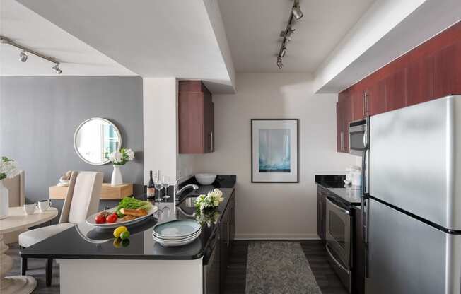 kitchen and living room of an apartment with stainless steel appliances and a black counter top