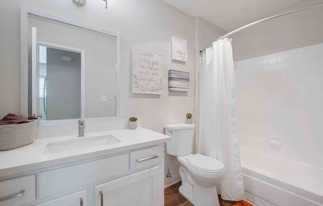 A white bathroom with a toilet, sink, and mirror.