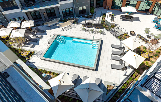 Aerial view of the refreshing swimming pool at The Mint Rahway, surrounded by lounging areas and umbrellas, ideal for residents of this luxury apartment rental community.
