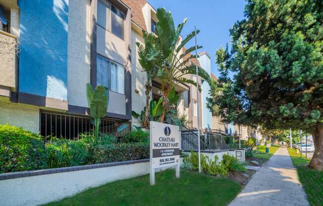 an apartment building with a sign in the grass in front