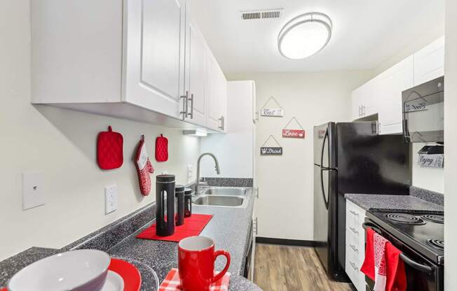 A kitchen with black appliances and red accents.