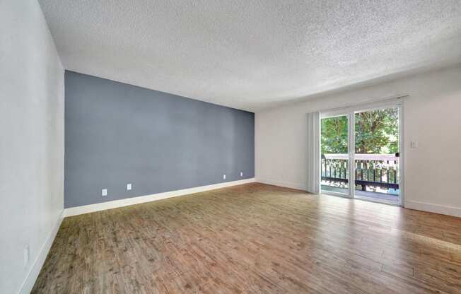 a living room with hardwood floors and a sliding glass door to a balcony