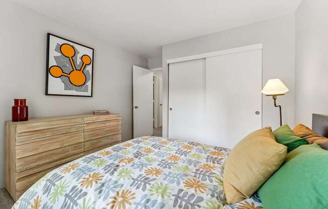 A bedroom with a bed, a dresser, and a painting on the wall.