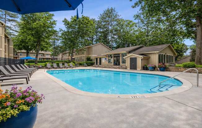 A swimming pool surrounded by lounge chairs and trees.