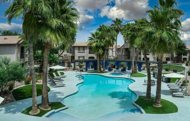 A swimming pool surrounded by palm trees and lounge chairs.
