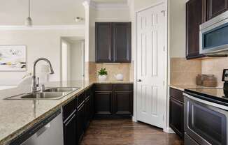 A kitchen with a sink, stove, and cabinets.