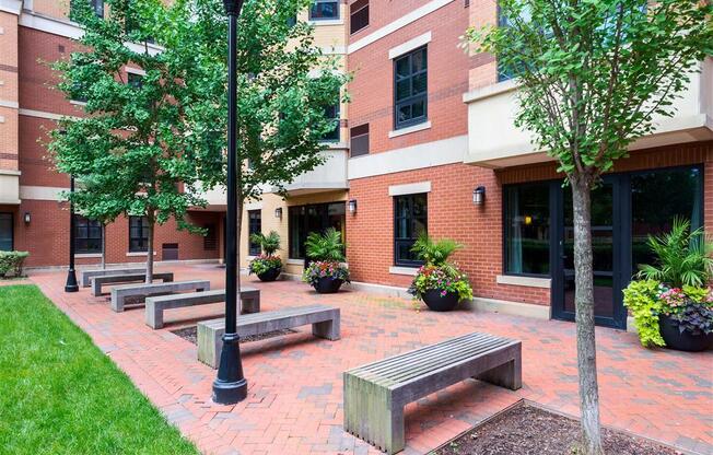 a courtyard with benches in front of a brick building