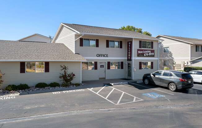 a white building with a parking lot and a car parked in front of it