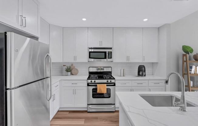 a white kitchen with stainless steel appliances and white cabinets