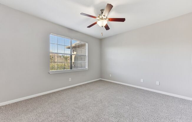 A room with a ceiling fan and a window with blinds.