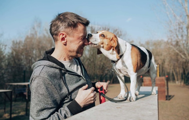 Image of a man and his Beagle dog smiling happily. We are a pet friendly community.