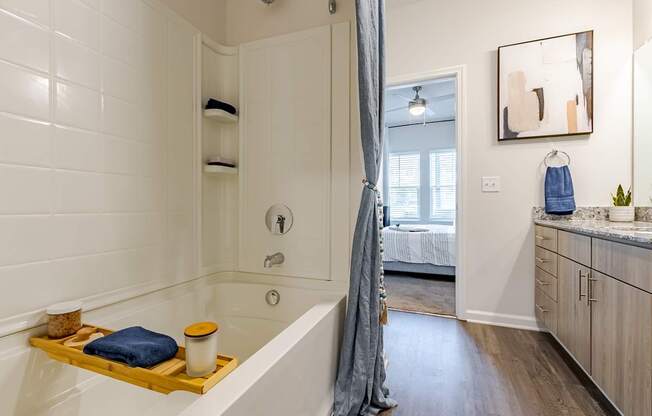 A bathroom with a white tub and wooden shelf.