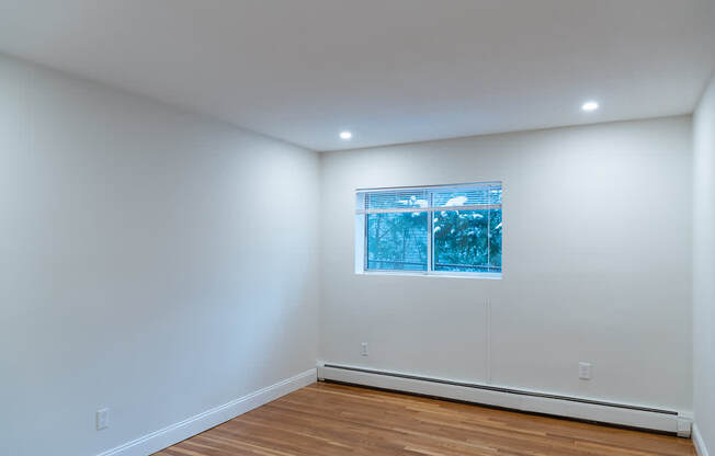 A room with a window and wooden floors.