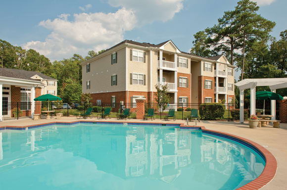 Pool with pergola, chairs and umbrellas; apartment building