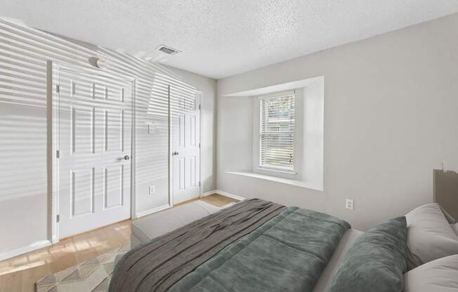 A bedroom with a bed, two closets, and a window.