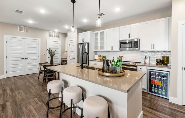 a kitchen with white cabinets and a large island with bar stools