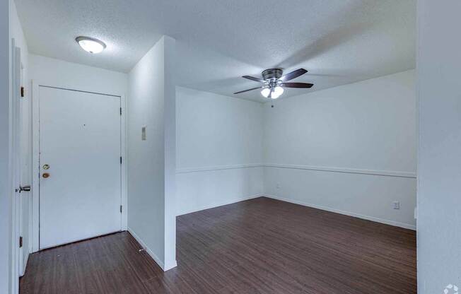 A room with a ceiling fan and wooden flooring.