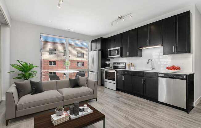 a living area with a couch coffee table and a kitchen with black and white cabinetry