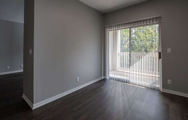 an empty living room with a large window and wood floors