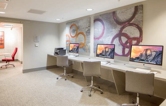 a conference room with four computer desks and a mural on the wall