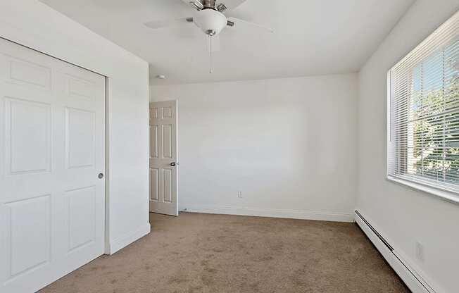 an empty bedroom with white walls and a ceiling fan