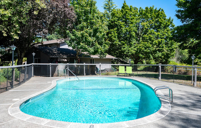 a pool with a fence around it and a house in the background