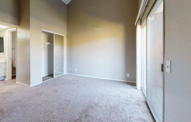 Apartments Ontario CA - Rancho Vista - Unfurnished Bedroom With Connected Bathroom Sink and Counter, Plush Carpet Floors, and Natural Light From the Sliding Glass Door