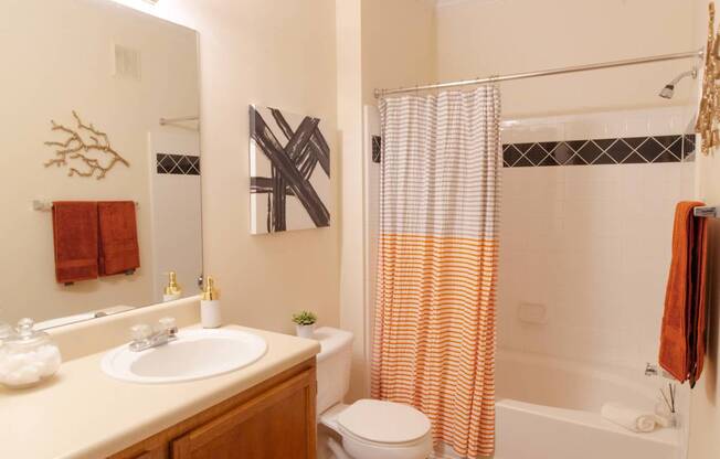 A bathroom with a white sink, toilet, and shower curtain.