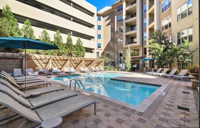 A large swimming pool surrounded by sun loungers and umbrellas.