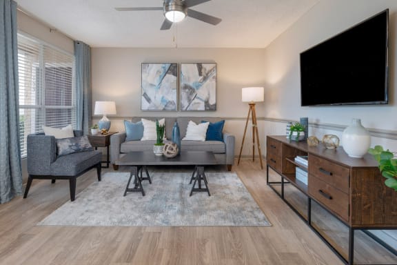 Living room with large window, modern flooring and paint colors, and ceiling fan at Preserve at Cedar River Apartments, Florida