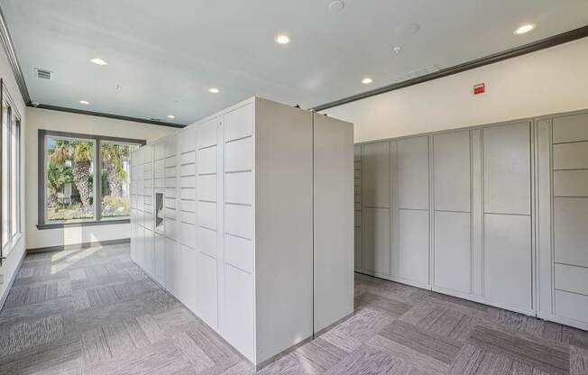 A room with a grey carpet and white cupboards.