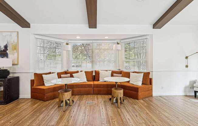 A living room with a large orange couch and wooden floors.