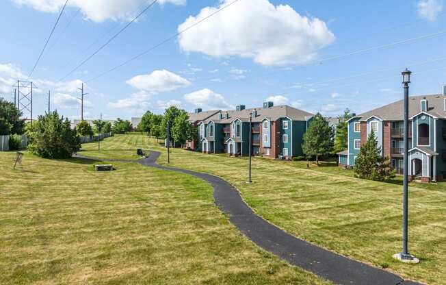 a path through a grassy area next to a row of houses