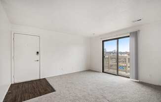 A living room with plush carpet and a slider to a private balcony with a view at Normandy Village Apartments, Michigan City, 46360