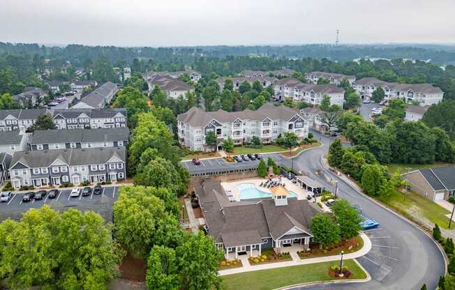 A bird's eye view of a residential area with houses, a swimming pool, and a parking lot.